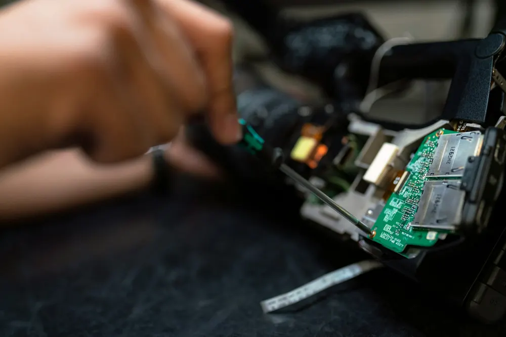 Mani di un tecnico al lavoro su una scheda elettronica con attrezzi da cablaggio